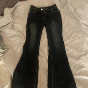 Svarta bootcut jeans - Snygga svarta bootcut jeans med klassisk femficksdesign och kontrastsömmar.  midwaist och stretchigt jeansmaterial. Står storlek  S. använt få tal gånger så väldigt bra skick!