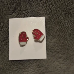 Röda örhängen formade som vantar - Charmiga örhängen i form av röda vantar med vita detaljer. Perfekta för att ge en lekfull touch till din outfit.