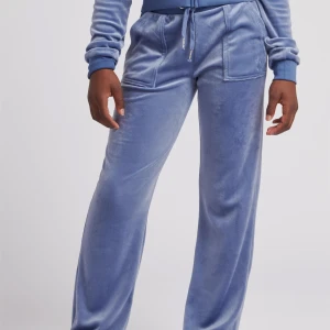 Blåa juicy byxor - Snygga och bekväma blå mjukisbyxor i mjukt material. Byxorna har en avslappnad passform med snörning i midjan och praktiska fickor framtill. Perfekta för en chill dag hemma eller en avslappnad promenad.
