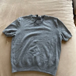 Grå kortärmad tröja från H&M Divided - Säljer en stilren grå kortärmad tröja från H&M Divided. Tröjan är i ett mjukt material med ribbade kanter vid ärmslut och nederkant. Perfekt för en avslappnad look.