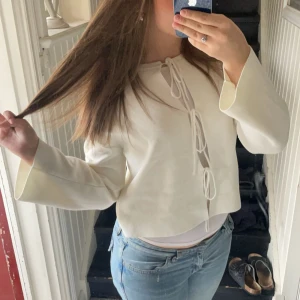 Vit tröja från Gina Tricot - Säljer en stilren vit tröja från Gina Tricot med knytning framtill. Tröjan har långa ärmar och en bekväm passform. Perfekt för en avslappnad look. 🖤