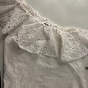 Vit offshoulder topp från Mango - Säljer en söt vit offshoulder topp från Mango med volangdetaljer. Köpt 2023 och använd få gånger så i bra skick🤍
