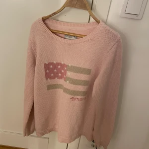 Rosa stickad tröja från lexington - Säljer en söt rosa stickad tröja från lexington med ett amerikanskt flaggmotiv på framsidan. Tröjan har långa ärmar och en rund halsringning. Perfekt för en avslappnad stil. Storlek M men passar mig med S