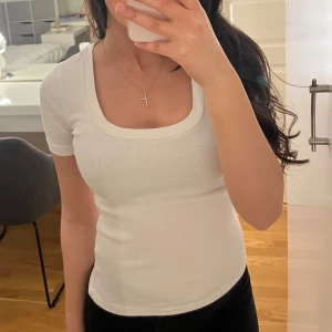 Vit ribbad t-shirt - Säljer en stilren vit ribbad topp med korta ärmar och rund halsringning. Perfekt för en enkel och snygg look. Passar bra till både jeans och kjol.