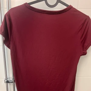 Vinröd t-shirt - Säljer en enkel och stilren vinröd t-shirt med korta ärmar. Perfekt för en avslappnad look. T-shirten har en rund halsringning och är gjord i ett mjukt material.