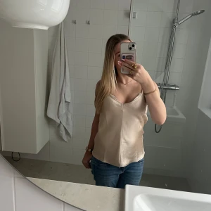 Beige linnetopp från H&M - Säljer en stilren beige linnetopp från H&M. Toppen har en v-ringad design och är ärmlös, perfekt för varmare dagar. Den är tillverkad i ett mjukt och bekvämt material som ger en elegant look.