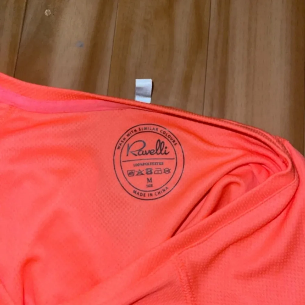 Säljer en neon rosa träningstopp från Ravelli i storlek M. Toppen är kortärmad och har en v-ringad design. Perfekt för träning med sitt lätta och bekväma polyester-material.. Neuletakit & Villapaidat.