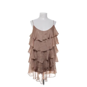 Volang klänning  - Säljer en brun klänning med flera lager volanger och tunna axelband. Perfekt för en somrig look med sin luftiga design och korta längd.