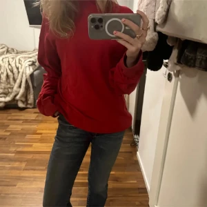 Röd sweatshirt från Champion - Säljer en snygg röd sweatshirt från Champion. Tröjan har långa ärmar och det klassiska Champion-logotypen på bröstet och ärmen. Perfekt för en avslappnad stil. Storlek: Man XS