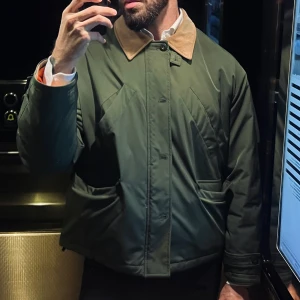 Grön jacka med krage - Snygg grön jacka med klassisk krage och knappar framtill. Jackan har en stilren design med långa ärmar och en diskret ficka på sidan. Perfekt för en stilren look.