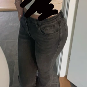 Grå bootcut jeans - Snygga grå bootcut jeans med hög midja och dragkedja. Perfekta för en trendig look. De har klassiska femfickor och en knappdetalj framtill.