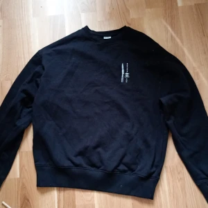 Svart sweatshirt från James Harvest - Säljer  2X svart sweatshirt från James Harvest med tryck av knivar och texten 'Satake Omo' på både fram- och baksidan. Tröjan har långa ärmar och en rund halsringning. Perfekt för dig som gillar unika tryck! Erbjuder 600 för båda och 350 för en. Pris kan diskuteras 