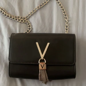 Valentino väska - Jättesnygg handväska med silver detaljer från mario valentino! Lite rostig på vissa ställen (se bilder) och vissa tecken på användning främst på baksidan. Jag köpte den på vinted, själv har jag använt den en del men fortfarande fin. Lång silver kedja. Två fack inuti.