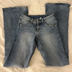 Blå jeansbyxor - Snygga blå jeansbyxor med klassisk femficksdesign och knappgylf. Perfekta för en avslappnad stil. De har en rak passform och är tillverkade i slitstarkt denim.