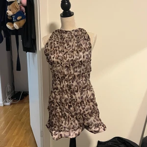 Leopard klänning - Snygg ärmlös klänning med leopard mönster . Klänningen har en halterneck-design med knytband i nacken. Perfekt för en somrig dag eller en avslappnad kväll. Storlek xs/s