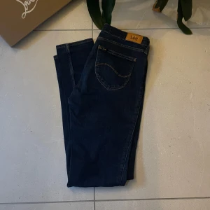 Mörkblå jeans från Lee - EliteVolt.  Snygga mörkblå jeans från Lee med klassisk femficksdesign och en läderpatch med logotyp baktill. Perfekta för en stilren look. De har en normal passform och är tillverkade i slitstarkt denim.