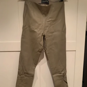 By Marlene Birger Beige/gröna skinnbyxor Elenasoo  - Snygga beige skinnbyxor från By Malene Birger i 100% fårskinn. Byxorna har en stilren design med en tight passform som ger en elegant look. Perfekta för att lyfta vilken outfit som helst med en touch av lyx.Modellen är Elenasoo 