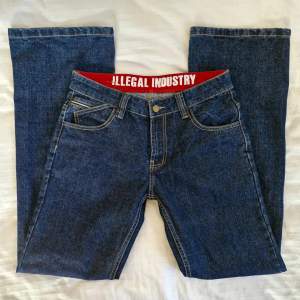 Jeans från Illegal Industry! Darkwash, utsvängda och lågmidjade med asymetriska fickor framtill.  Använda men i fint skick! Pris är förhandlingsbart :) Köpte dem nyligen av en tjej här på plick men de var för stora för mig, so saaad för de är verkligen sjukt snygga! Midjemått: 80 cm Totallängd: 108 cm Innerbenslängd: 81 cm Benvidd nedtill: 26 cm 