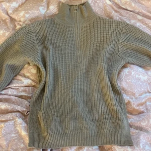 Beige stickad tröja från Shein - Säljer en beige stickad tröja från Shein med dragkedja och hög krage. Perfekt för kyliga dagar med sin mysiga och varma design. Tröjan har långa ärmar och ribbade kanter för extra komfort.