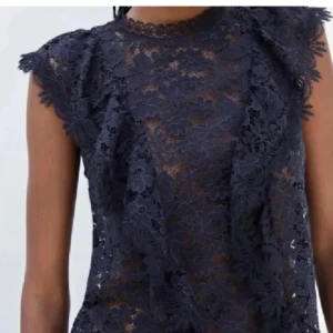 Mörkblå spetsblus - Elegant mörklblå spetsblus med blommigt mönster och korta ärmar. Perfekt för en stilfull look med vackra detaljer i spets.