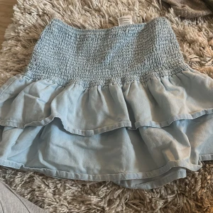 Ljusblå volangkjol från H&M - Söt ljusblå kjol från H&M med volangdetaljer och smockad midja. Endast använd fåtal gånger💖 går alltid att diskutera pris och bara att skriva för fler bilder☺️