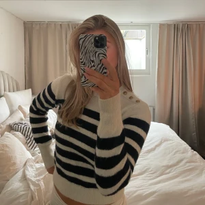 Randig stickad tröja - Säljer en mysig randig stickad tröja. Den har knappar på axeln som en fin detalj.