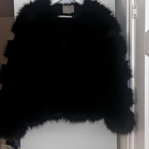 Svart pälsjacka - Snygg svart pälsjacka som ger en lyxig känsla. Perfekt för att hålla sig varm och stilren under kallare dagar. Jackan har en fluffig textur och en klassisk passform. Storlek Xl och den känns lite mindre i storleken.