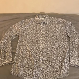 Lindberg Skjorta - Snygg blommig skjorta från Lindbergh i svart och vit. Skjortan har långa ärmar och en klassisk krage. Perfekt för att ge en stilren touch till din outfit. 