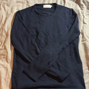 Mörkblå tröja från Casual Friday - Säljer en stilren mörkblå tröja från Casual Friday. Tröjan är långärmad och tillverkad i ett mjukt material som passar perfekt för kyligare dagar.