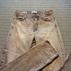 Grå jeans från Jack & Jones - Säljer ett par grå jeans från Jack & Jones med en loose fit. Byxorna har en klassisk femficksdesign och är tillverkade i ett slitstarkt denimtyg. Perfekta för en avslappnad stil. Köpta hos Jack n Jones, använda men inga större täcken på de. Hör av er vid frågor mvh Maxi. 