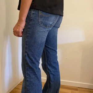 Blå jeans från Lee - Snygga blå jeans från Lee med bootcut och lågmidjade. De är i storlek 34 och är långa i benen. 