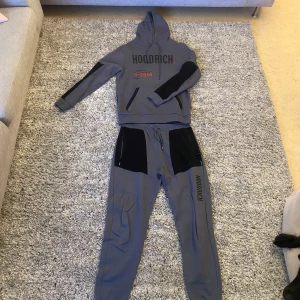 Tracksuit från Hoodrich - Säljer en grå hoodie och matchande byxor från Hoodrich. Hoodien har svarta detaljer och text på bröstet samt en justerbar huva. Byxorna har svarta paneler och dragsko i midjan. Perfekt för en avslappnad stil. Hoodie är storlek M och byxorna är L. ca 1399:- nypris. Om du önskar ytterligare info eller specifika bilder så är det bara att skriva 🙏
