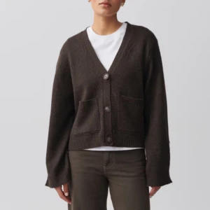 Brun stickad kofta - Säljer en mysig brun stickad kofta med knappar framtill och två praktiska fickor. Perfekt för en avslappnad stil. Koftan har en lös passform och långa ärmar. Nypris 495kr, helt slutsåld och endast använd 1 gång 