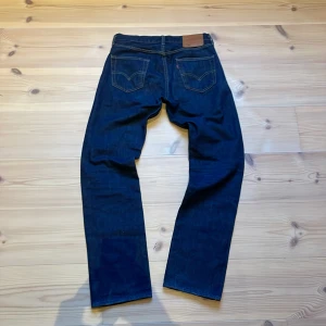 Levi’s Jeans 501 - Snygga mörkblå jeans med klassisk femficksdesign och kontrastsömmar. De har en rak passform och är tillverkade i slitstarkt denim. Perfekta för en avslappnad stil.