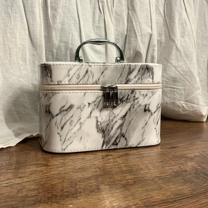 Marmormönstrad väska med handtag - Snygg och stilren väska med marmormönster och praktiskt handtag. Perfekt för att förvara smink eller småsaker. Väskan har en dragkedja för säker förslutning.