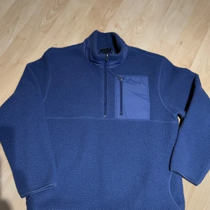 Blå fleece tröja från H&M - Säljer en blå fleece tröja från H&M med dragkedja och bröstficka. Perfekt för kyliga dagar med sin Thermolite-teknologi. Tröjan har används ett par gånger och tvättad 1 gång nu innan säljning. 