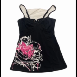 Emo topp - Snyggt svart topp  med rosa tryck från metal mulisha . Toppen har en öppen rygg med snörning!! Skriv om ni vill ja bättre bilder 