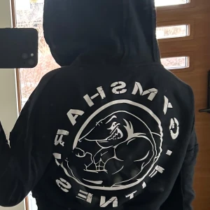 Svart hoodie från Gymshark - Säljer en svart hoodie från Gymshark med dragkedja och huva. Den är croppad. Knappt använd.