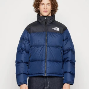 Blå och svart dunjacka från The North Face - Säljer en blå och svart dunjacka från The North Face. Jackan har en dragkedja framtill och är långärmad. Perfekt för kyliga dagar med sin pufferdesign som håller värmen.