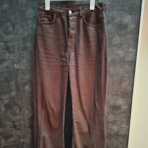 Bruna jeans med regular wide fit - Snygga bruna jeans med en regular wide passform. De har en klassisk design med fem fickor och knappgylf. Perfekta för en avslappnad stil. W29 , L32