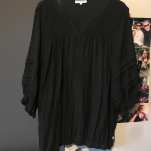 Svart blus från Zhenzi - Snygg svart blus från Zhenzi med trekvartsärmar och v-ringad hals. Blusen har fina volangdetaljer på ärmarna och en lös passform som ger en bekväm känsla. Om man är lite kortare skulle jag säga att man även kan använda den som en fin lite pösigare klänning på sommaren 