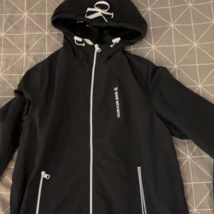 Svart vindjacka från Calvin Klein - Snygg svart vindjacka från Calvin Klein använd max 3 ggr sedan bara hängt hemma skicket är sprillans nytt och inget sönder och inga märken på den. Storlek S 