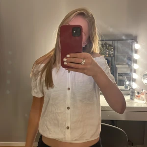 Vit offshoulder topp från Hampton Republic - Säljer en söt vit offshoulder topp från Hampton Republic. Toppen har knappar framtill och en elastisk kant vid axlarna som gör att man kan ha den på flera olika fina sätt. Perfekt för varma sommardagar!💕