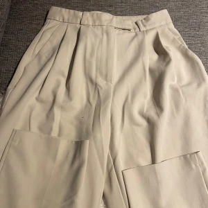 Beige byxor från NA-KD - Snygga beige byxor från NA-KD med hög midja och raka ben. Byxorna har en stilren design med dragkedja och hyska fram. Perfekta för en chic och avslappnad look.