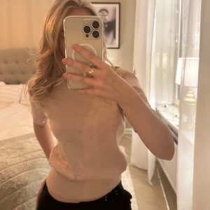 Rosa stickad t-shirt - Säljer en stilren rosa topp med korta ärmar. Tröjan har en mjuk och bekväm passform, perfekt för en avslappnad look. Den är enkel att matcha med olika outfits.