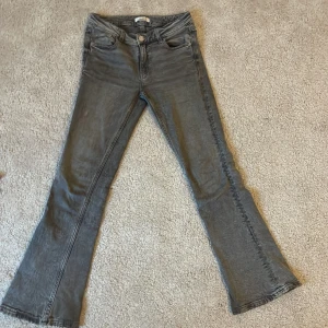 Grå bootcut jeans - Snygga grå bootcut jeans med en klassisk femficksdesign. De har en knapp och dragkedja framtill och är perfekta för en avslappnad stil. Passar bra till både sneakers och stövlar.