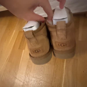 UGG ULTRA MINI BRUNA - Säljer ett par klassiska bruna UGG boots i mocka. De är varma och bekväma, perfekta för kyligare väder. Storlek 40. Kommer med box och kvitto.