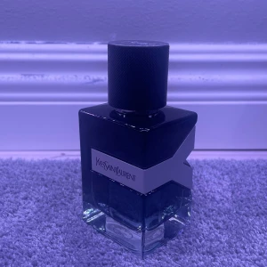 Yves Saint Laurent parfym - Säljer en elegant parfym från Yves Saint Laurent. Flaskan har en stilren design med en mörkblå ton och en svart kork med YSL-logotypen. Perfekt för den som vill ha en sofistikerad doft. Perfekt för året runt. 75% vätska kvar i flaskan av 50ml. 