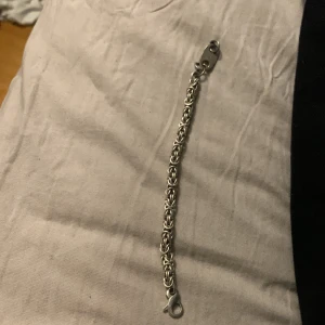 Silverfärgat armband - Snyggt silverfärgat armband med en intrikat kedjedesign. Armbandet har en praktisk karbinhake för enkel på- och avtagning. Perfekt för att ge en stilren touch till din outfit.