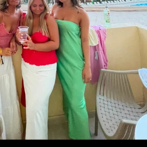 Grön bandeau långklänning - Snygg grön axelbandslös långklänning med en elegant passform. Perfekt för sommarens festligheter. Klänningen har en stilren design som framhäver figuren. Öppen rygg 